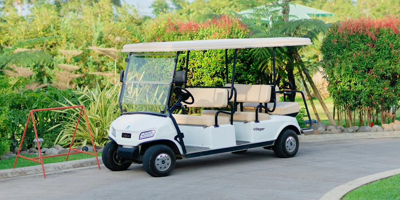 White six-passenger golf cart parked on a palm-lined resort drive