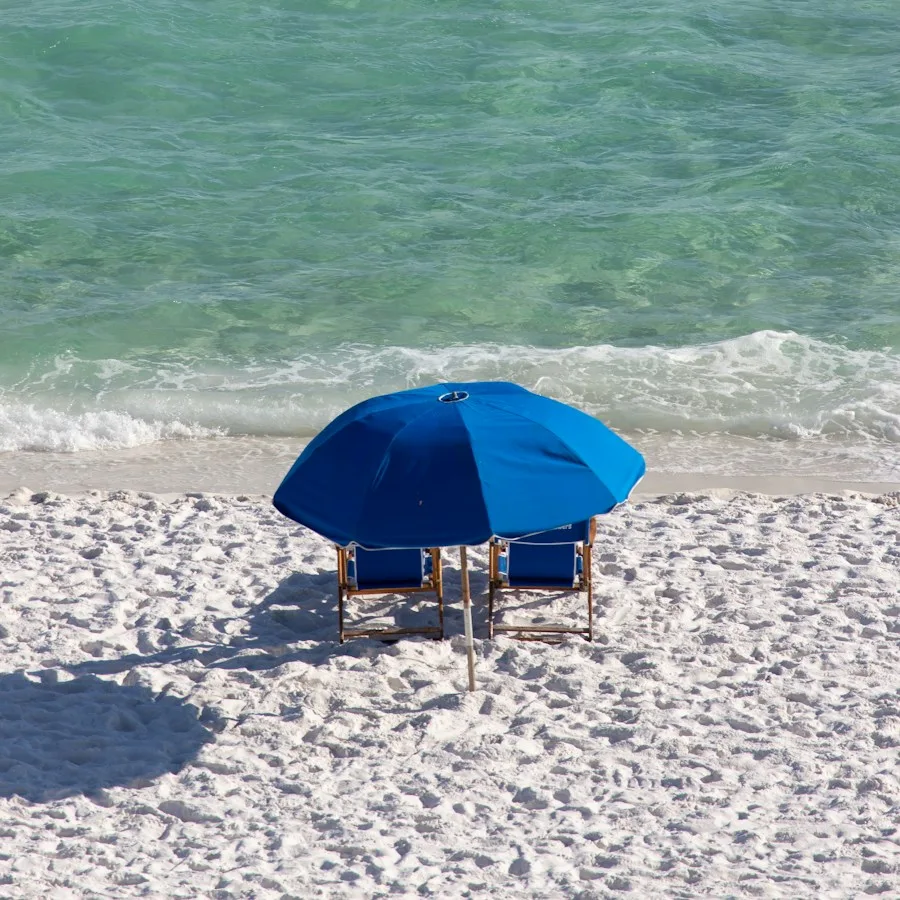 Blue beach umbrella and chairs on white sand